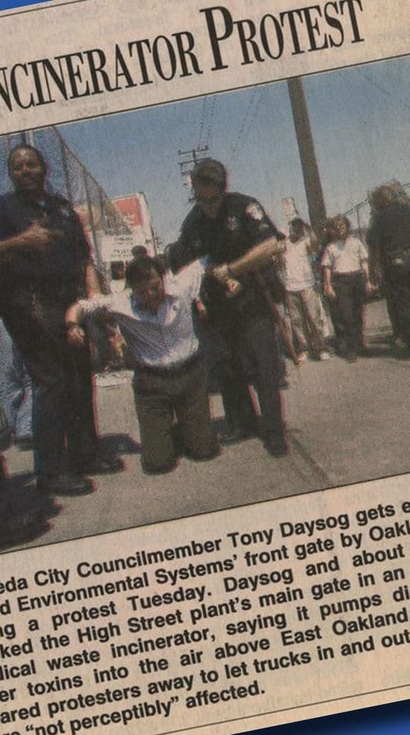 Newspaper photograph of Councilmember Tony Daysog being carried away from a gate by two Oakland police officers during a 2001 protest.