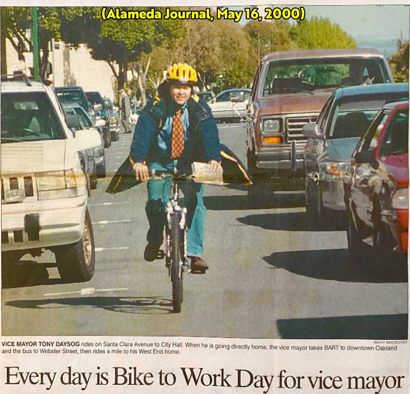 Alameda Journal clipping from May 16, 2000, headlined “Every day is Bike to Work Day for vice mayor”: Vice Mayor Tony Daysog, in a yellow helmet and a tie, rides his bike on Santa Clara Avenue to City Hall. The caption says that when he goes directly home he takes BART to downtown Oakland and the bus to Webster Street, then rides a mile to his West End home.